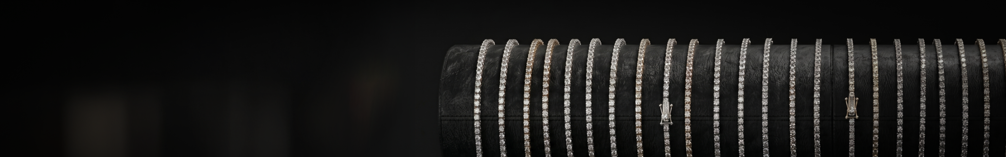 Tennis bracelets arranged in a receding procession on a dark surface — demonstrating scale and consistent supply